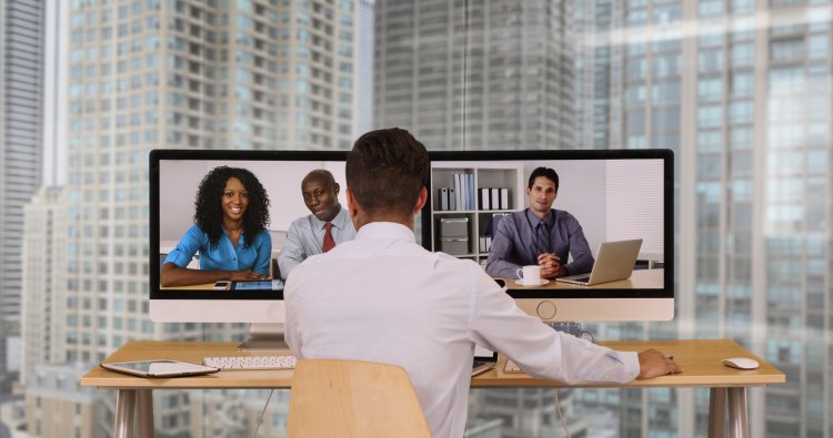 nextiva enterprises voip service man in white shirt video conferencing people on computer monitors